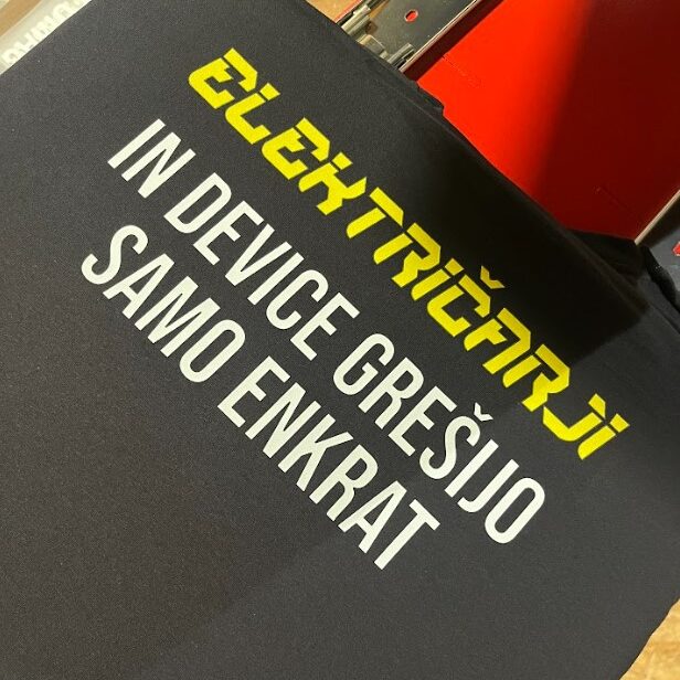 Črna majica s toplotnim transferjem smešnega napisa o električarjih.