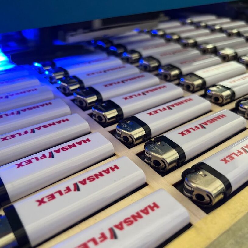 UV tisk logotipa Hansaflex na promocijske vžigalnike – personalizacija promocijskih izdelkov