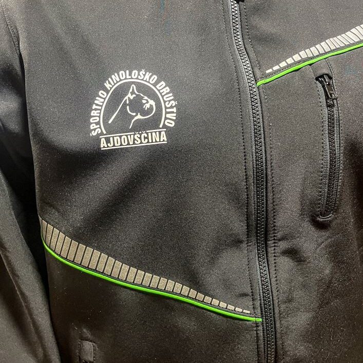 Toplotni transfer logotipa Športnega kinološkega društva Ajdovščina na črno softshell jopico.